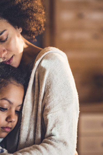 African American mother and daughter embracing at home.